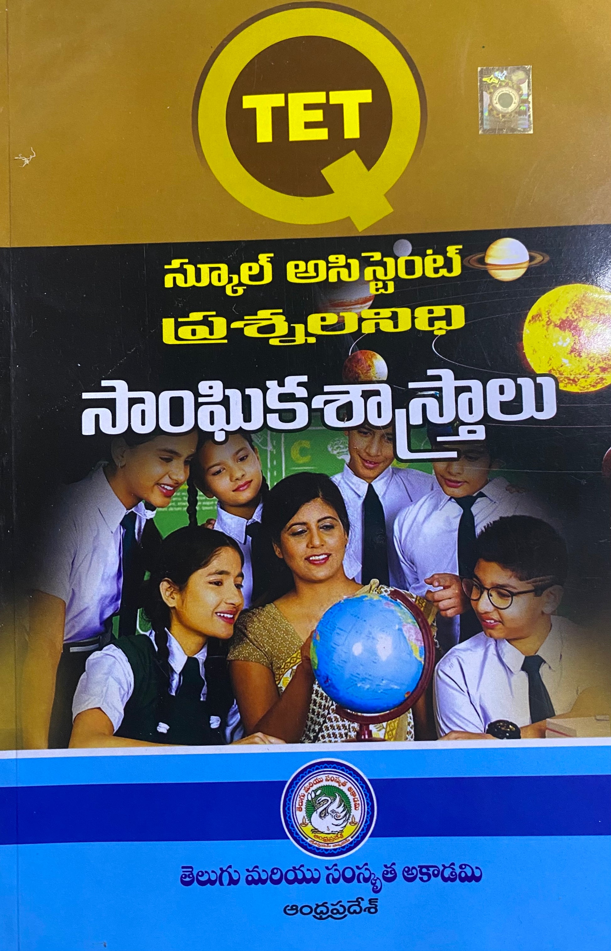 The cover of the "TET School Assistant Question Bank Social Science" in Telugu medium by Telugu Academy, showing a teacher and students with a globe.