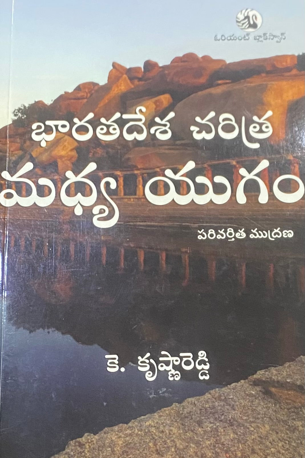 The book cover of Bharatadesa Charitra Madhya Yugam displays the title in white Telugu script against a backdrop of rocky terrain and temple ruins reflecting in a water body.